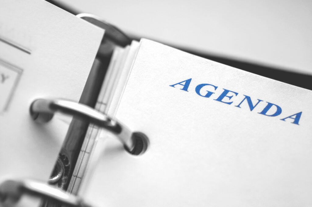 Daily agenda paper planner closeup. Black and white picture with blue word Agenda in focus